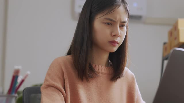 疲惫的年轻亚洲女性使用笔记本电脑，在长时间使用电脑工作后，在家庭办公室感觉眼睛疲劳。视频素材