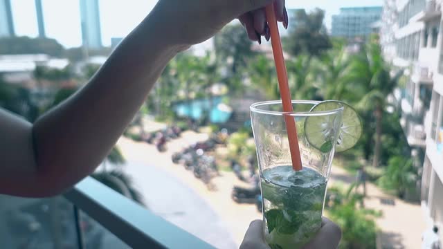 女人拿着饮料，从酒店阳台上看风景视频下载