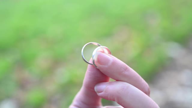 一个女人在户外用手指拿着两个结婚戒指。德国。视频下载