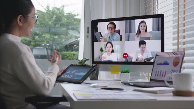 女商人在视频会议上谈论销售报告。亚洲团队使用笔记本电脑和平板电脑进行在线视频会议。在家工作，远程工作和在家自我隔离视频下载