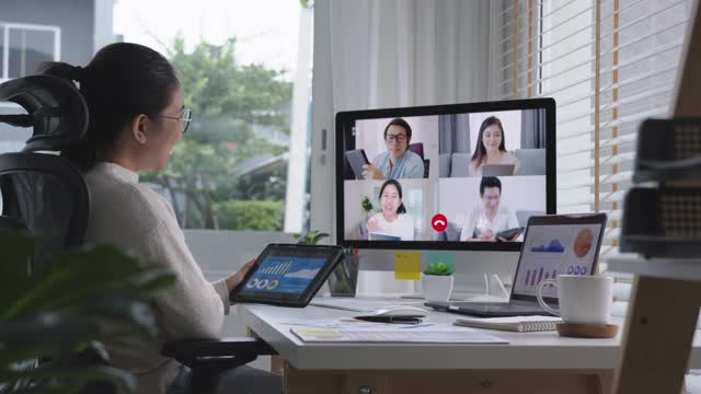 女商人在视频会议上谈论销售报告。亚洲团队使用笔记本电脑和平板电脑进行在线视频会议。在家工作，远程工作和在家自我隔离视频素材