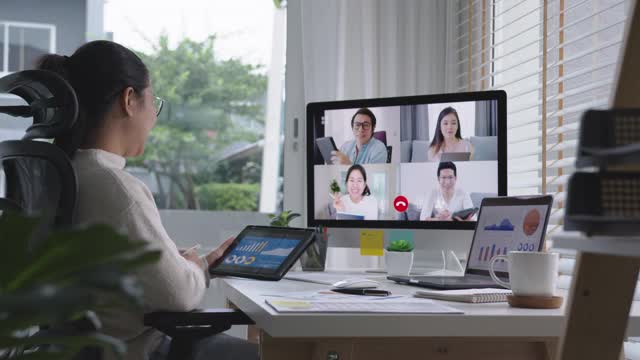 慢速放大女商人在视频会议中谈论销售报告。亚洲团队使用笔记本电脑和平板电脑进行在线视频会议。在家工作，远程工作和在家自我隔离视频素材