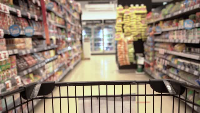 模糊的购物车和购物车缓慢地通过食品货架内部散焦超市背景。视频素材