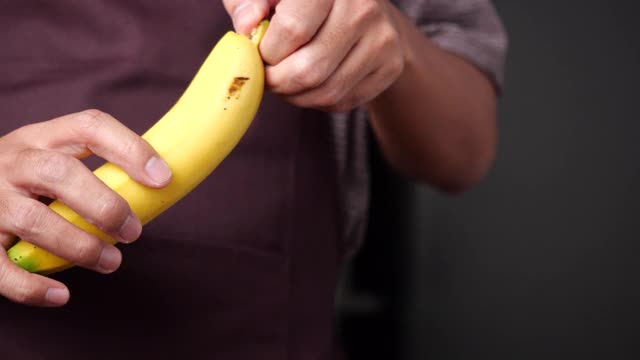 男人用手剥香蕉。香蕉滑块或摄影车拍摄4K慢镜头视频素材