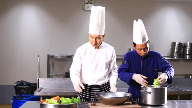 两位亚洲厨师在厨房里做沙拉。视频素材