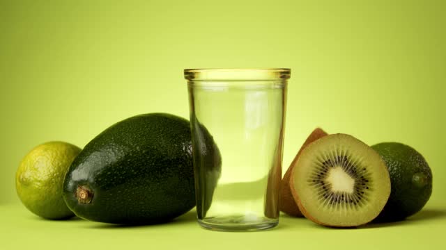 绿色的果汁倒进一个极简主义背景的玻璃杯视频素材