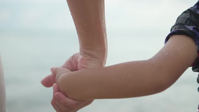 快乐的父亲和小儿子手牵着手走到海边。慢动作视频素材