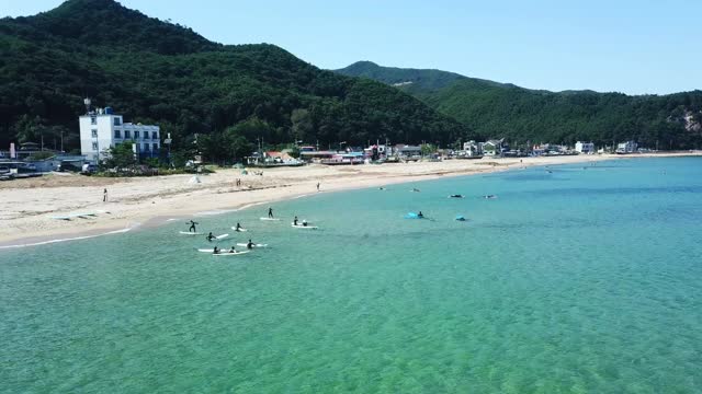 韩国江原道东海寺大津海滩上的人们在冲浪视频素材