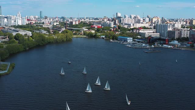 城市码头上有许多帆船穿过湖面。视频。鸟瞰图美丽的夏季景观与许多白色的船航行在湖上现代城市的背景视频素材