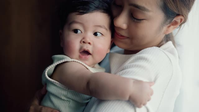 年轻的亚洲母亲抱着她可爱的儿子视频下载
