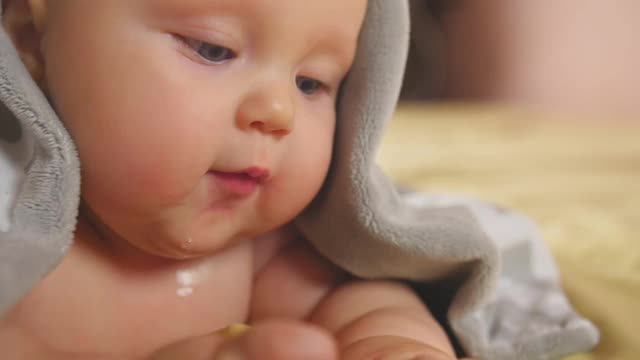 一张四个月大的胖乎乎的婴儿的肖像，盖着一条灰色的毯子躺在肚子上。近距离射杀。视频下载
