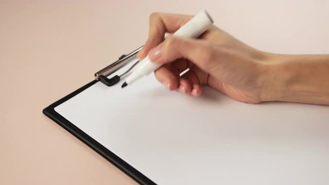特写的女孩手写在记事本上。用记号笔在白纸上写一份计划。视频素材