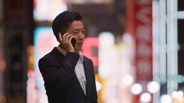 一位日本商人在大阪新世街夜生活区使用电话视频素材