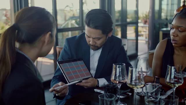 一名日本商人在商务午餐期间用平板电脑做演示视频素材
