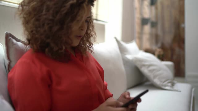 一个快乐的女人在家里使用智能手机的肖像视频下载