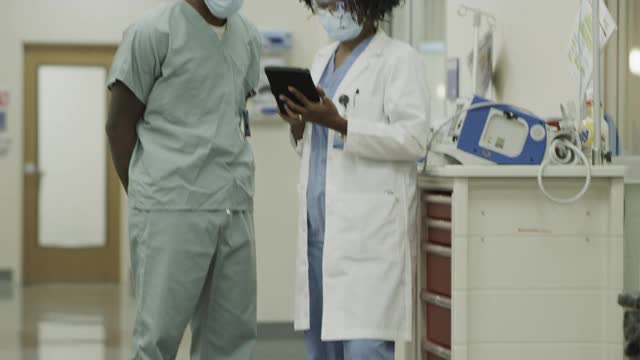 在美国犹他州盐湖城医院，医生和护士戴着外科口罩使用数字平板电脑视频素材
