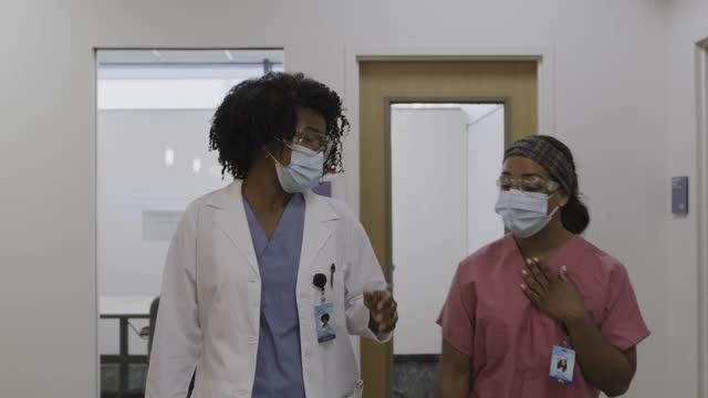医生和护士戴着外科口罩在医院走廊交谈的慢动作跟踪镜头/盐湖城，美国犹他州视频素材