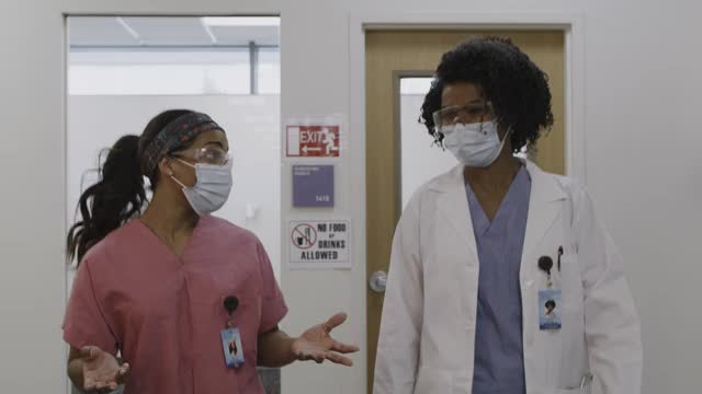 美国犹他州盐湖城，医生和护士戴着外科口罩在医院走廊交谈的跟踪镜头视频素材