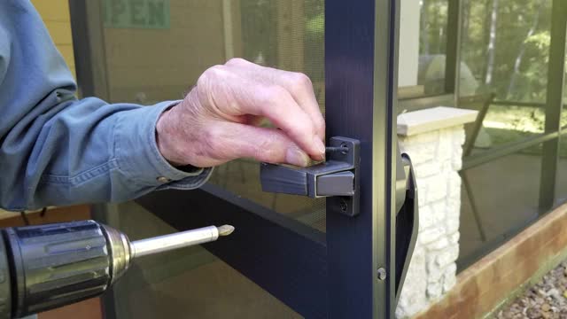 安装或修理纱门上新的门闩的工人或房主。视频下载