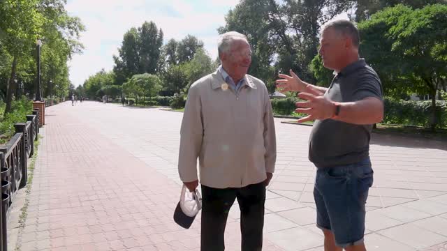 白种人英俊的年轻成年男子与老父亲聊天时，走在城市的街道上视频素材