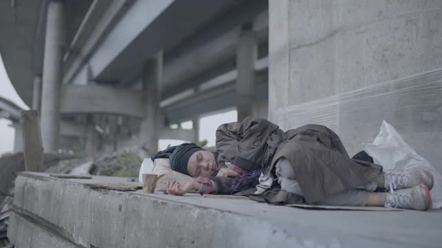 无家可归的女人穿着脏衣服，睡在地上，社会问题视频素材