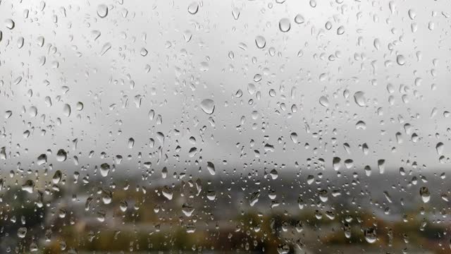 雨滴落在窗户上，抽象的背景。沉闷的雨天和雨滴上的窗户玻璃在阴沉的秋天的一天模糊的背景特写视频素材