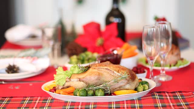 感恩节或圣诞节晚餐的餐桌在背景上用手倒香槟的女人。前景是塞满馅的烤火鸡。庆祝传统节日视频素材
