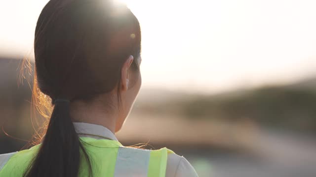 慢镜头近距离的一个女工程师把一个建筑头盔在日落，成功，工作和工程概念。视频下载
