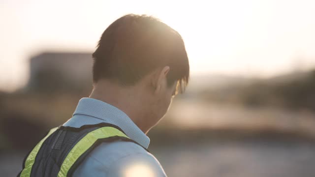 慢镜头近距离的一个男性工程师把一个建设头盔在日落，成功，工作和工程概念。视频素材