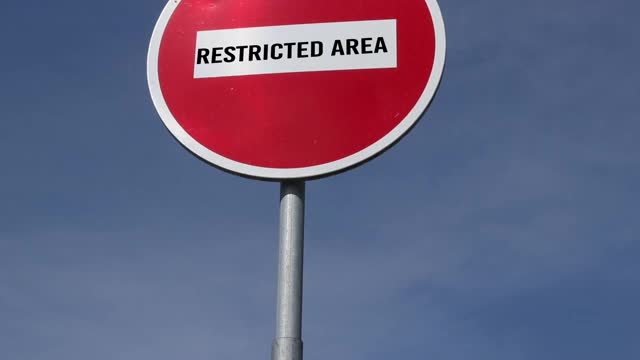 蓝色天空背景下的红色道路标志和文字限制区域禁止进入。危险区域的概念视频素材