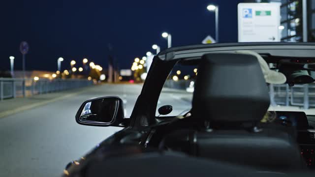 一名女子开着一辆黑色敞篷车，在晚上被开了罚单后进入停车场。视频下载