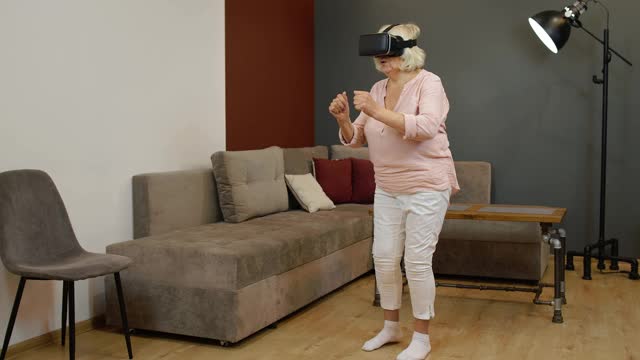快乐的老女人戴着虚拟现实头盔眼镜，试着触摸一些东西，看3D视频视频素材