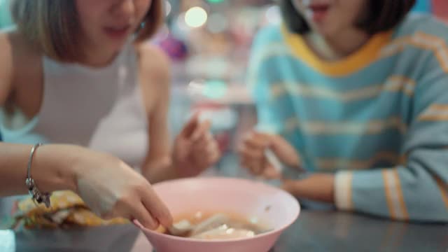 两个快乐的女人享受着第一次吃街头小吃视频素材