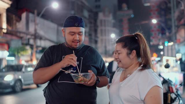 一对甜蜜的情侣在曼谷Yaowarat路享受街边小吃视频素材