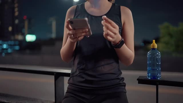 亚洲跑步者在跑步过程中使用电子设备听音乐。视频下载