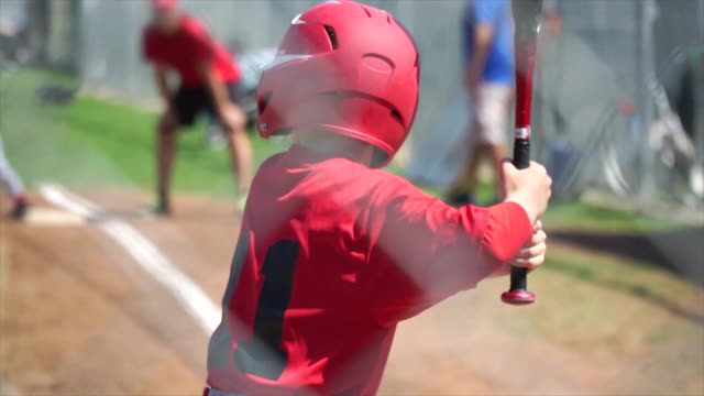一个小男孩在打少年棒球联盟时击球。——慢动作视频下载