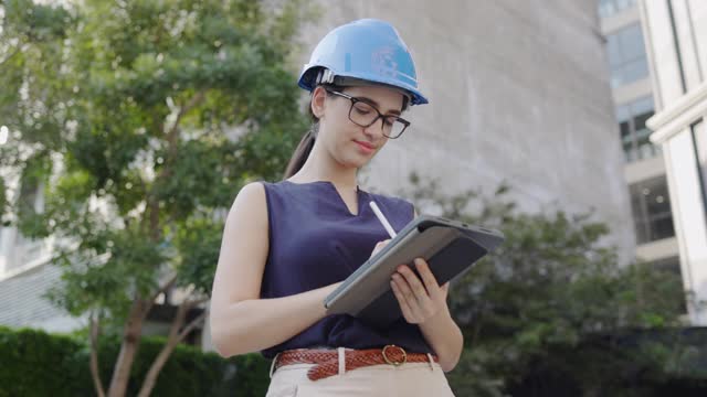 戴安全帽的女工程师用写字板记录建筑工作。工作时戴安全帽。建筑维修服务及施工现场。概念的关键员工视频素材