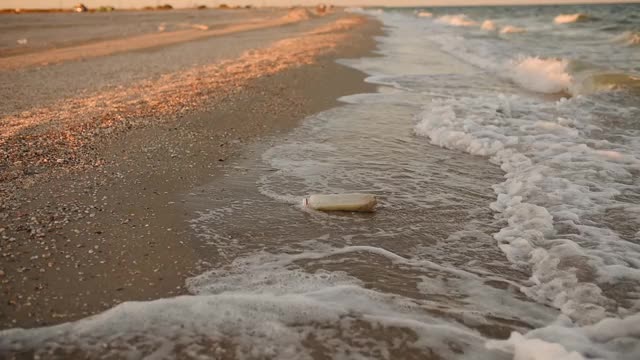 海浪把废弃的塑料垃圾带到沙滩上视频素材