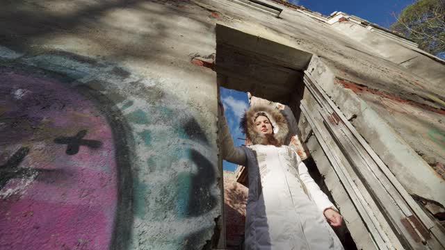 女人透过破旧的房屋，石头建筑废墟的窗框望出去视频下载