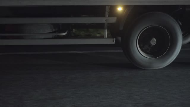 一个半挂车车轮在夜间高速公路上运动的特写。视频下载