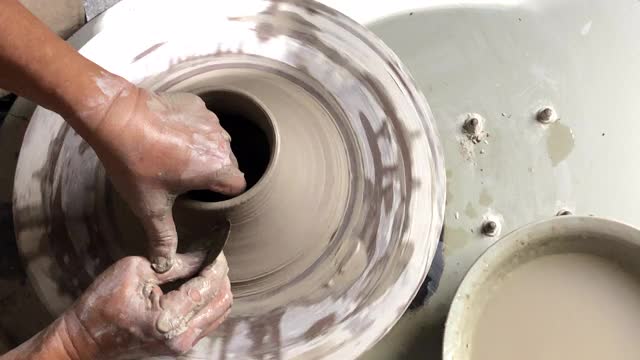 亚洲华人高级陶艺师在他的工艺工作室里，在一个旋转的陶轮上制作陶器视频下载