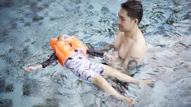 父亲在游泳池里教儿子游泳视频素材