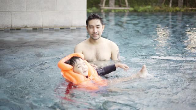 父亲在游泳池里教儿子游泳视频素材