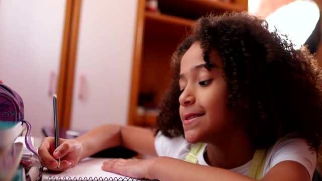 黑人女学生在家学习。女孩子在做家庭作业，写笔记视频素材