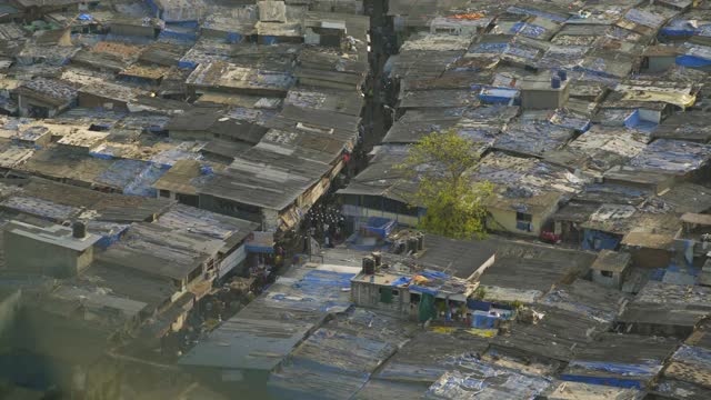 在摇摇欲坠的建筑物和杂乱的屋顶之间的高海拔购物人群——孟买，印度视频下载
