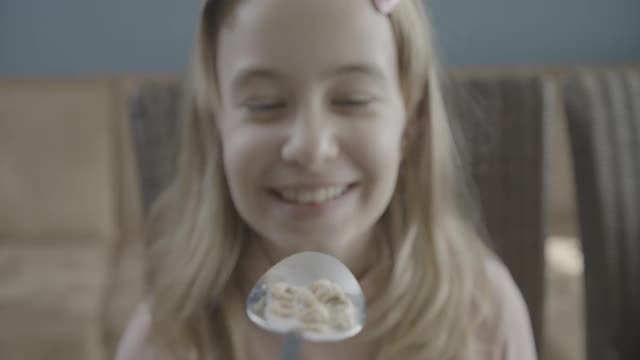 微笑的少女吃着一勺麦片玉米片视频素材