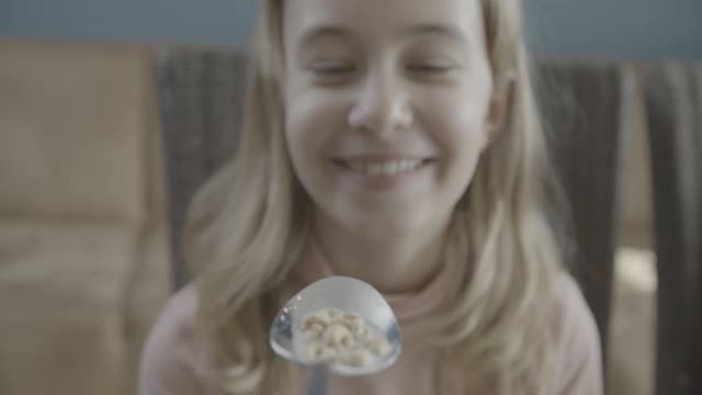 微笑的少女吃着一勺麦片玉米片视频素材