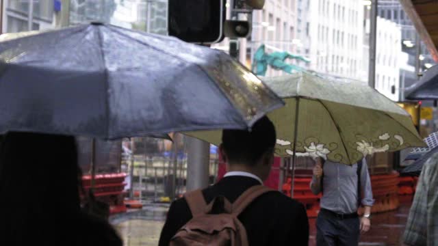 慢镜头:季风期间，人们撑着雨伞在城市里行走——澳大利亚悉尼视频下载