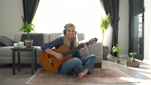 一个在家里弹吉他的美丽成熟女人的肖像。视频下载