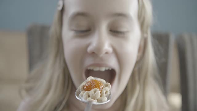 微笑的少女吃一勺麦片玉米片慢镜头视频素材